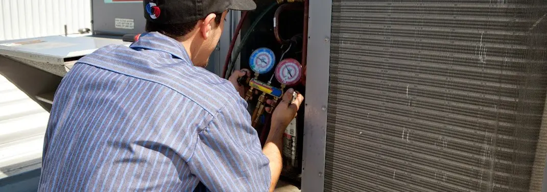 HVAC technician servicing a condenser unit in Quartz Hill